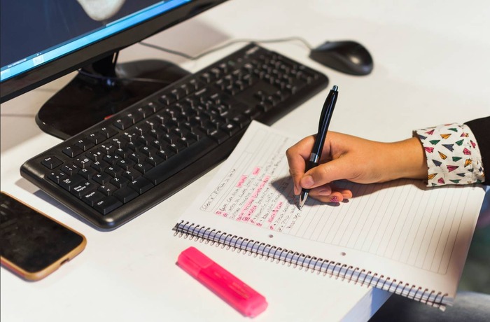 Person writing a personal letter at home desk near window