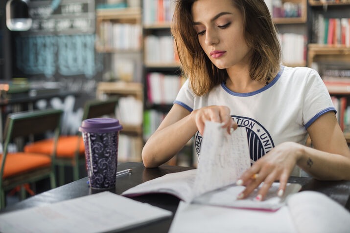 Woman reviewing and proofreading book pages in a library before publication